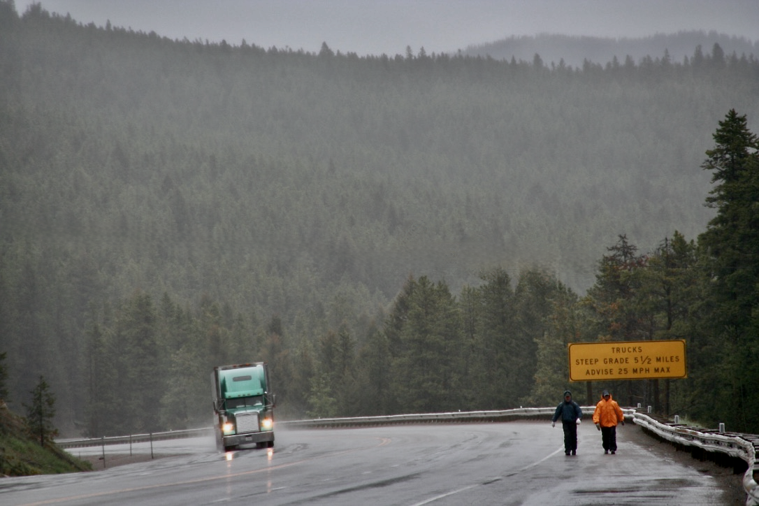 Walking the rainy mountain road as a semi truck passes